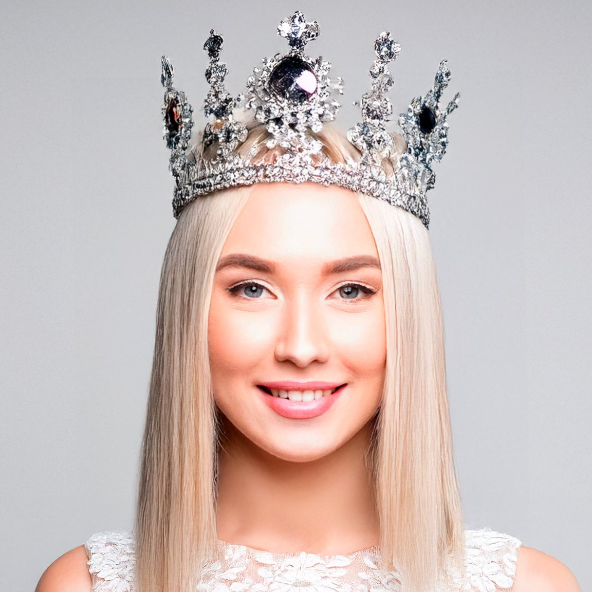 Blonde oman wearing a sparkling tiara against a gray background
