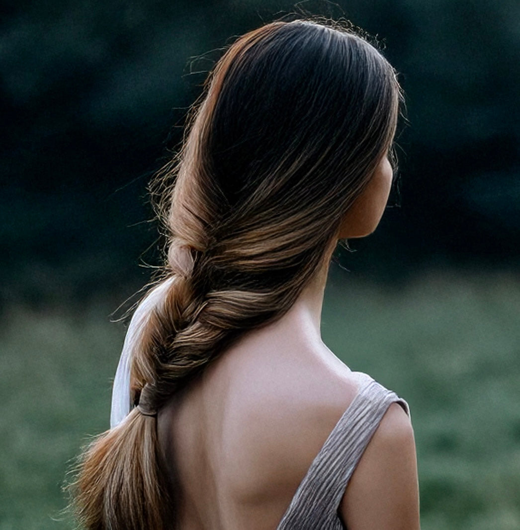 The back view of a woman with a beautiful hair braid in a meadow